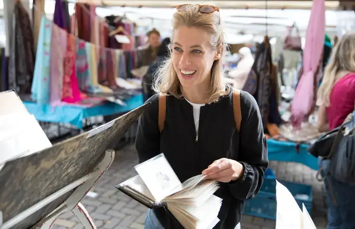 Une femme consulte un livre dans une brocante