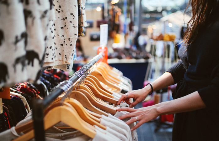 Une femme fait du shopping et cherche parmi des vêtements présentés sur des cintres